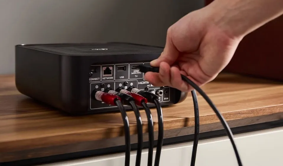 Speaker cables being connected to the rear panel of a Denon Home Amp
